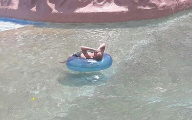 Person relaxing on an inflatable tube in a lazy river at Splash Jungle Water Park, Phuket.