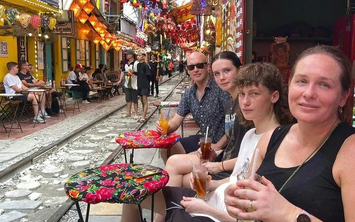Group enjoying drinks at a colorful street cafe along Hanoi's train street during motorbike tour.