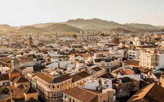 Malaga cityscape with historic buildings and mountains in the background.