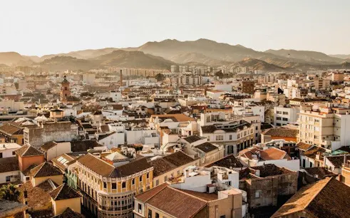 Malaga cityscape with historic buildings and mountains in the background.