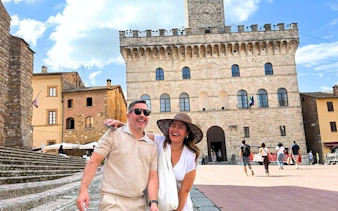 Couple smiling in front of Palazzo Comunale in Montepulciano, Italy.