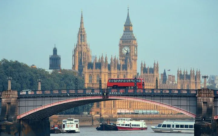 Red bus crossing Westminster Bridge with Big Ben in the background, London walking tour.