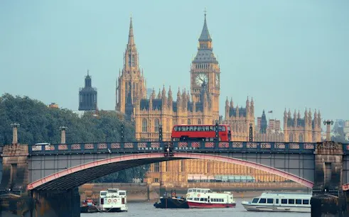 Red bus crossing Westminster Bridge with Big Ben in the background, London walking tour.