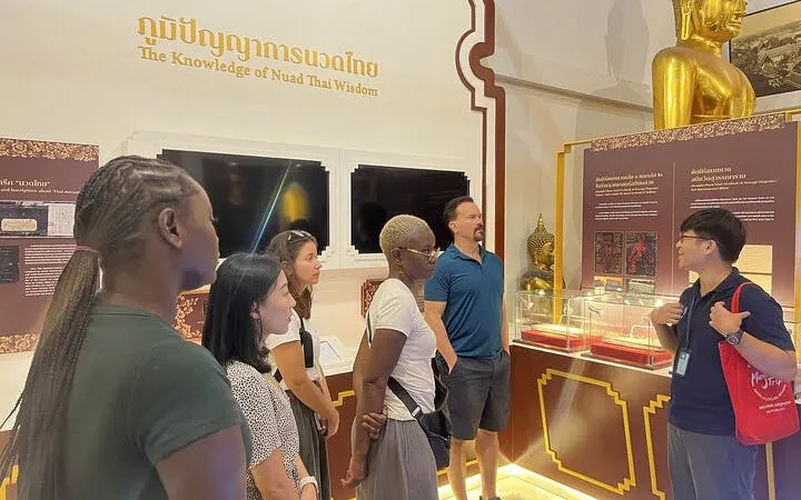 Group learning Thai massage techniques at Wat Pho temple exhibit in Bangkok.