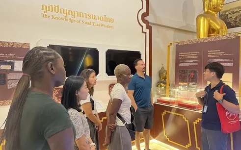 Group learning Thai massage techniques at Wat Pho temple exhibit in Bangkok.