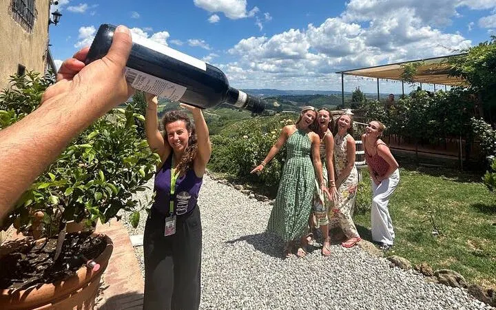 Tour group enjoying wine tasting at a Chianti winery with scenic views of San Gimignano.