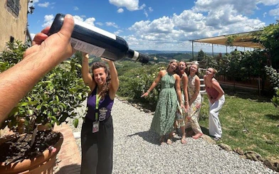 Tour group enjoying wine tasting at a Chianti winery with scenic views of San Gimignano.