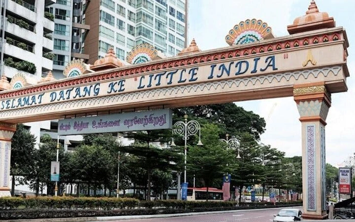 Entrance arch to Little India in Kuala Lumpur, featuring colorful decorations and nearby buildings.