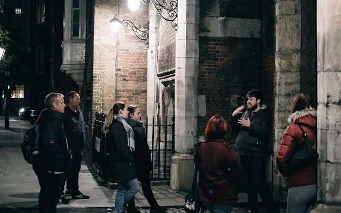 Group listening to guide during York haunted walking tour at night.