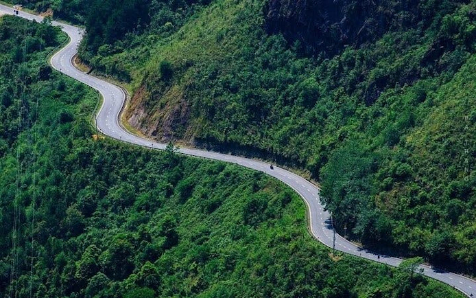 Winding road through lush green hills on Sapa motorbike tour route.
