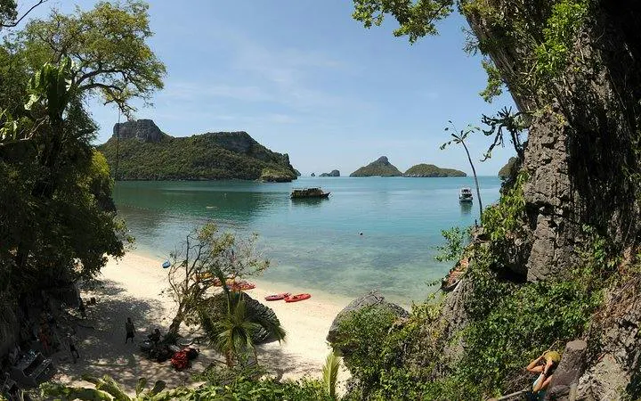Kayaks on a beach with limestone cliffs and islands in Ang Thong National Marine Park, Koh Samui.