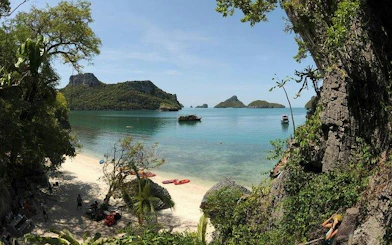 Kayaks on a beach with limestone cliffs and islands in Ang Thong National Marine Park, Koh Samui.