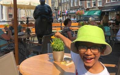 Child pointing at statue in Utrecht café during self-guided city exploration game.