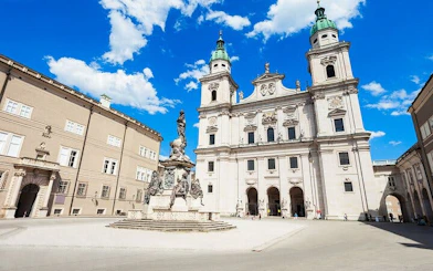 Salzburg Cathedral and Residenzplatz fountain under blue sky, Salzburg.
