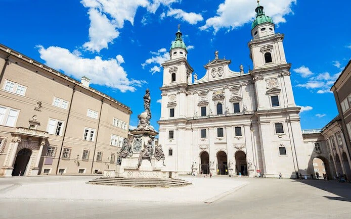 Salzburg Cathedral and Residenzplatz fountain under blue sky, Salzburg.