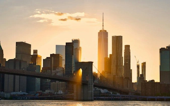 New York skyline with Brooklyn Bridge at sunset, featured in self-guided walking tour app.
