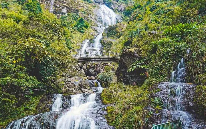 Sa Pa motorbike tour view of Silver Waterfall with lush greenery and bridge.