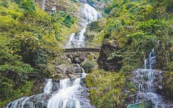 Sa Pa motorbike tour view of Silver Waterfall with lush greenery and bridge.