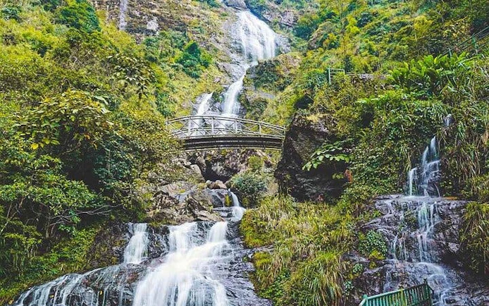 Sa Pa motorbike tour view of Silver Waterfall with lush greenery and bridge.