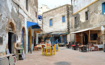 Essaouira street scene with colorful chairs and tables, Marrakech day trip.
