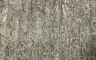 Hieroglyphics on ancient Egyptian stone wall, Model Village Egypt tour.