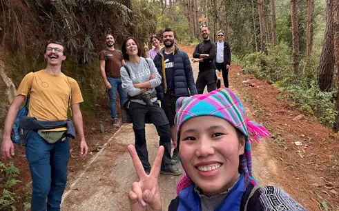 Group of tourists on a forest trail during a private car tour from Sapa to Mu Cang Chai rice terraces.