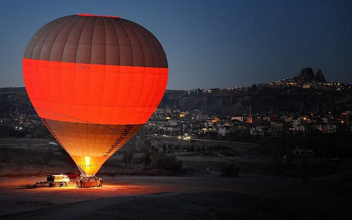 Hot air balloon preparing for sunrise flight over Cappadocia landscape.