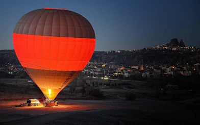 Hot air balloon preparing for sunrise flight over Cappadocia landscape.