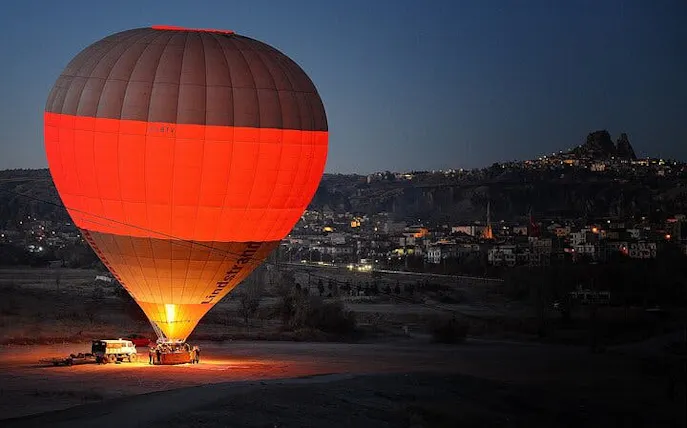 Hot air balloon preparing for sunrise flight over Cappadocia landscape.