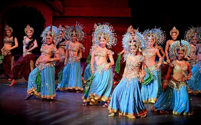 Performers in vibrant costumes dancing at Colosseum Show Pattaya, Thailand.