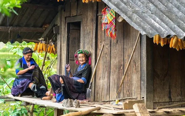 Local women sitting on a wooden porch in a remote Mu Cang Chai village, Vietnam.
