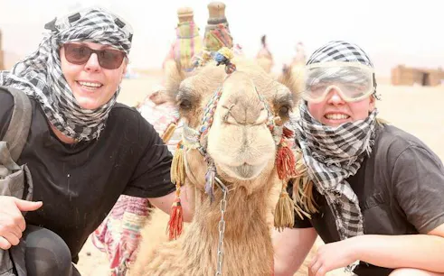 Super Safari participants with camel in Sharm El Sheikh desert.