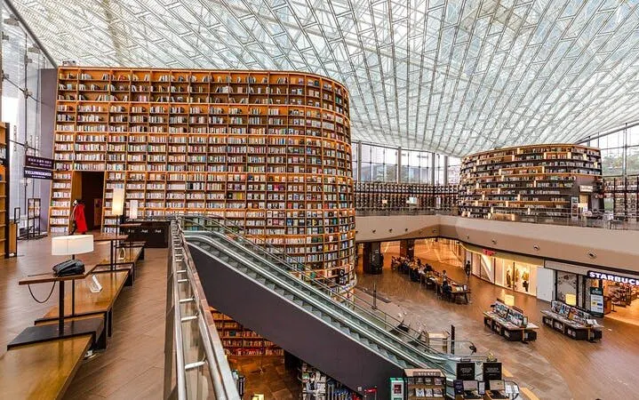 Seoul Starfield Library with towering bookshelves and escalator in modern mall setting.