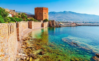 Ancient walls and Red Tower by the sea in Antalya, Turkey, featured in a self-guided walking tour app.