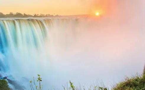 Victoria Falls at sunrise during a guided tour, mist rising from the waterfall.