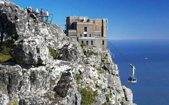 Cable car ascending Table Mountain with tourists at the viewpoint, Cape Town.