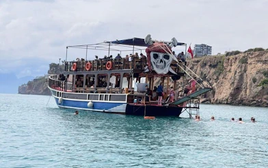 Boat tour near Antalya's Lower Duden Waterfall with passengers enjoying the view.