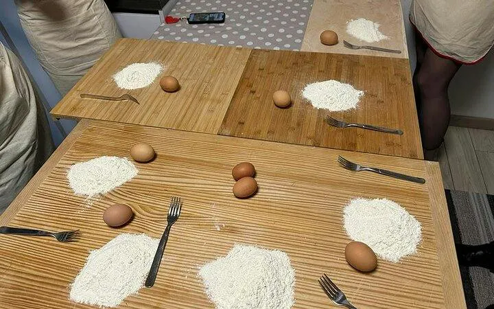 Pasta-making setup with flour, eggs, and forks on wooden boards in Modena cooking class.