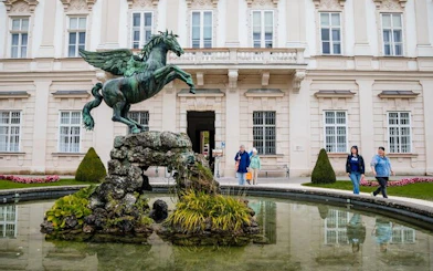 Pegasus statue in Mirabell Gardens, Salzburg, with visitors exploring nearby.