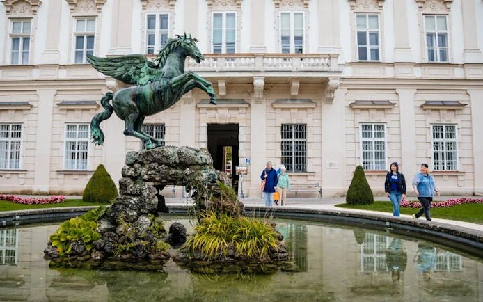 Pegasus statue in Mirabell Gardens, Salzburg, with visitors exploring nearby.