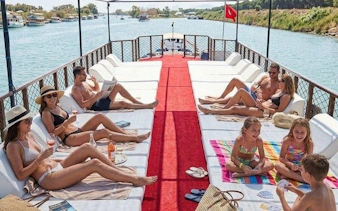 Boat tour group relaxing on deck with drinks, Antalya river view, part of Lower Duden Waterfall tour.
