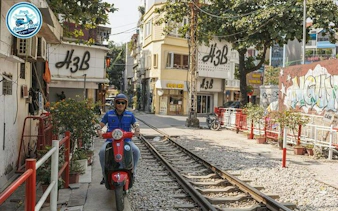 Vespa rider on Hanoi train street, exploring local sights and culture during half-day tour.