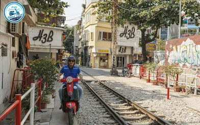 Vespa rider on Hanoi train street, exploring local sights and culture during half-day tour.
