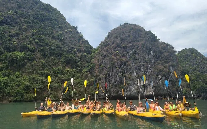 Kayakers in Lan Ha Bay with limestone cliffs in the background.