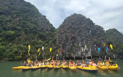 Kayakers in Lan Ha Bay with limestone cliffs in the background.