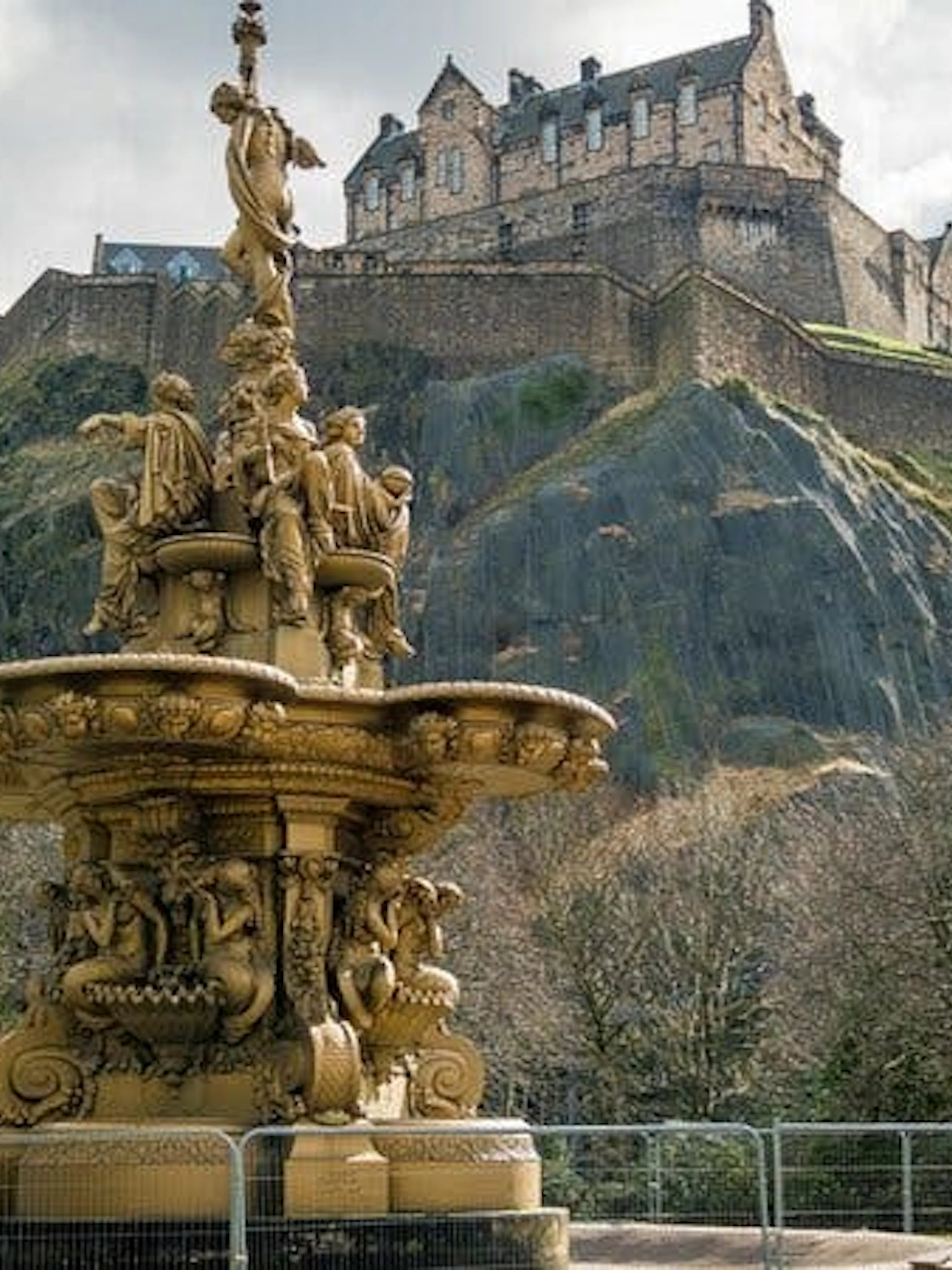 Edinburgh Castle atop Castle Rock with ornate fountain in foreground.