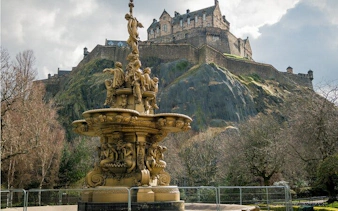 Edinburgh Castle atop Castle Rock with ornate fountain in foreground.