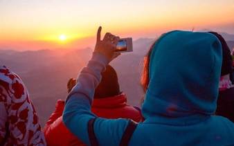 Tourists capturing sunrise on Moses Mountain during Saint Catherine Monastery tour from Sharm El Sheikh.