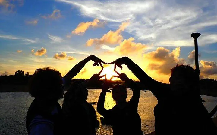 Group forming star shape with hands during sunset on Ishigaki Island SUP tour, Okinawa.