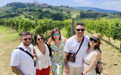 Tourists enjoying a vineyard in Tuscany with San Gimignano in the background.